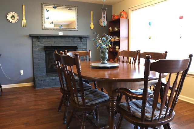 dining space featuring dark hardwood / wood-style flooring and a brick fireplace