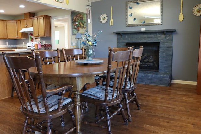 dining space with a brick fireplace and dark hardwood / wood-style floors