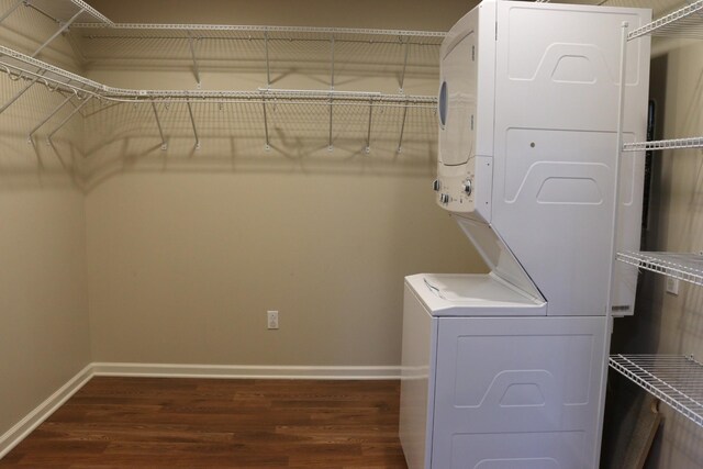 laundry room with dark hardwood / wood-style floors and stacked washing maching and dryer