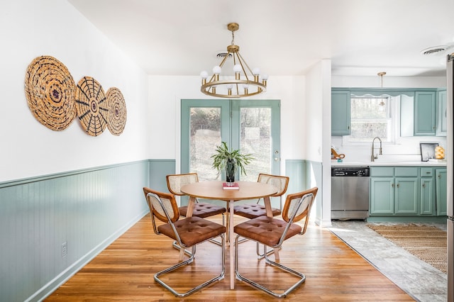 dining space featuring sink, light hardwood / wood-style floors, and a notable chandelier