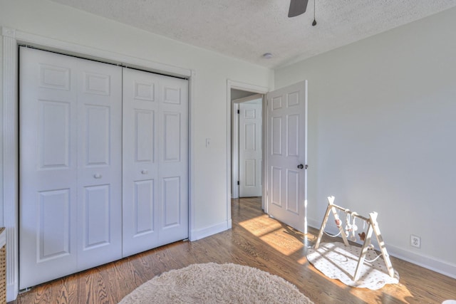 bedroom with wood-type flooring, a textured ceiling, a closet, and ceiling fan