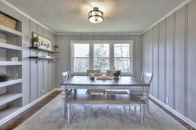 dining area with built in shelves, dark hardwood / wood-style flooring, a textured ceiling, and ornamental molding