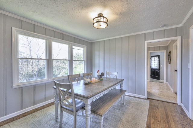 dining room featuring hardwood / wood-style floors, a textured ceiling, and crown molding