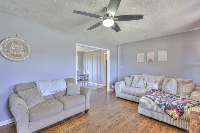 living room with ceiling fan, dark hardwood / wood-style flooring, and a textured ceiling