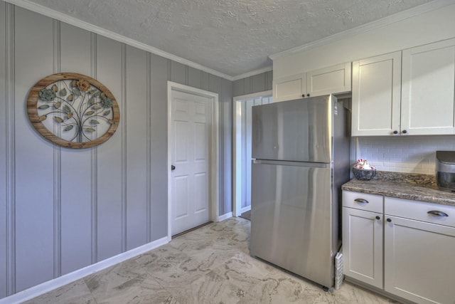 kitchen with stainless steel refrigerator, white cabinetry, tasteful backsplash, dark stone countertops, and ornamental molding