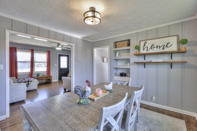 dining area featuring hardwood / wood-style flooring, ceiling fan, built in shelves, ornamental molding, and a textured ceiling