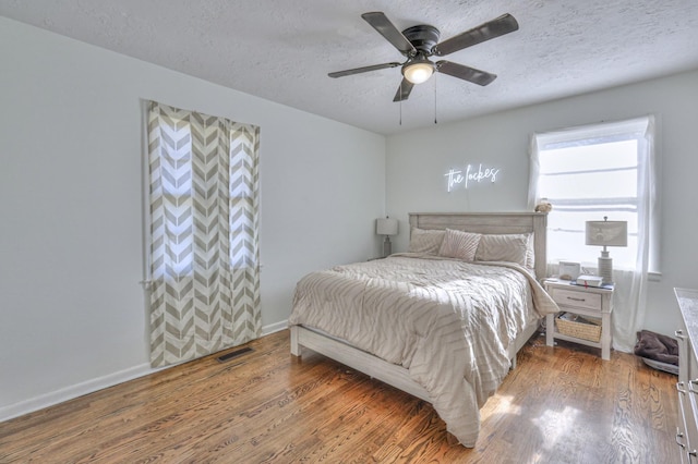 bedroom featuring a textured ceiling, ceiling fan, and dark hardwood / wood-style floors