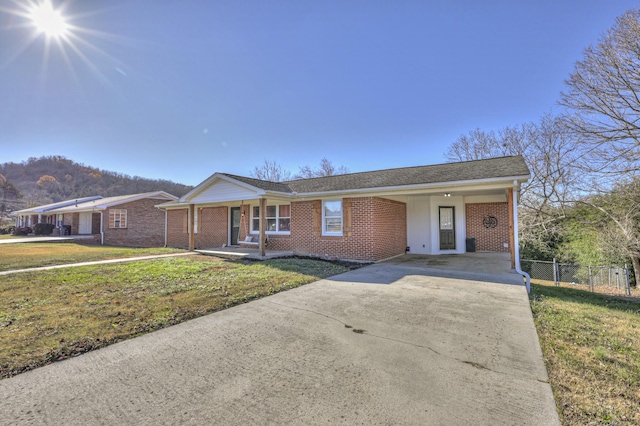 ranch-style home with a mountain view, a front lawn, a porch, and a carport