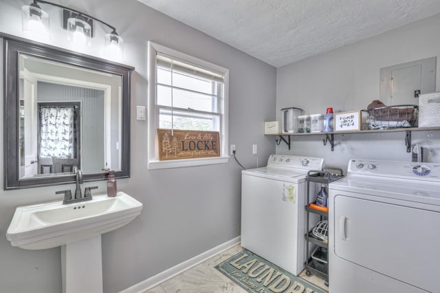 clothes washing area featuring separate washer and dryer, sink, and a textured ceiling