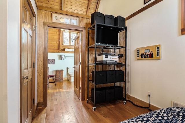 bedroom with hardwood / wood-style flooring, wooden ceiling, wooden walls, and vaulted ceiling