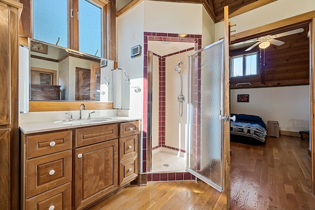 bathroom featuring wood-type flooring, vanity, ceiling fan, and a shower with shower door