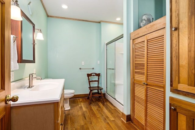 bathroom featuring a shower with door, vanity, wood-type flooring, and toilet