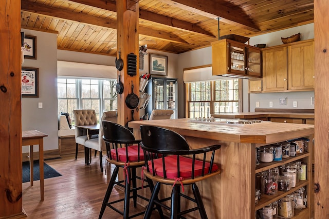 kitchen featuring dark hardwood / wood-style flooring, a breakfast bar, beam ceiling, wooden ceiling, and stainless steel gas stovetop