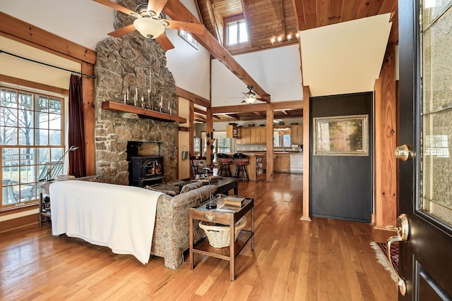 living room with hardwood / wood-style floors, high vaulted ceiling, a wood stove, and beam ceiling