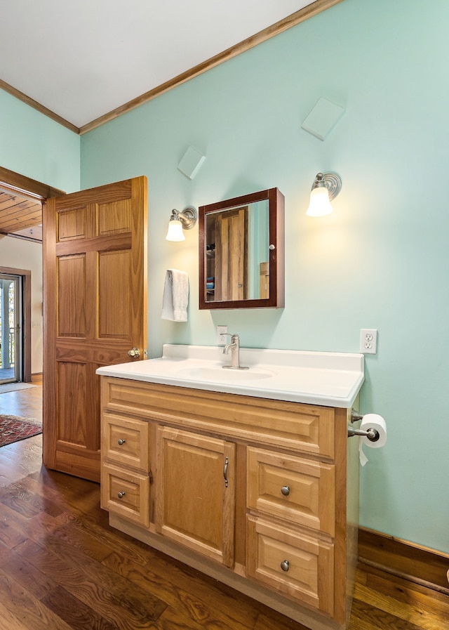 bathroom featuring wood-type flooring, vanity, and ornamental molding