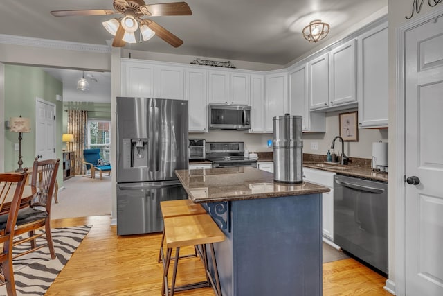 kitchen featuring appliances with stainless steel finishes, sink, dark stone countertops, a kitchen island, and a breakfast bar area