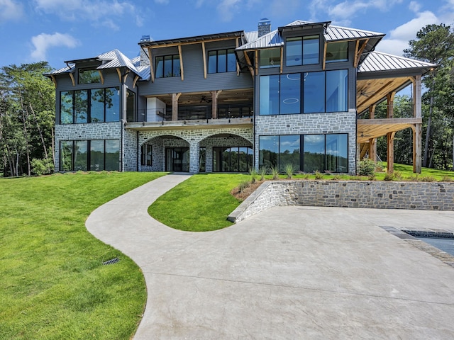 back of house with ceiling fan, a yard, and a balcony