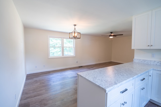 kitchen featuring kitchen peninsula, ceiling fan with notable chandelier, pendant lighting, hardwood / wood-style flooring, and white cabinetry