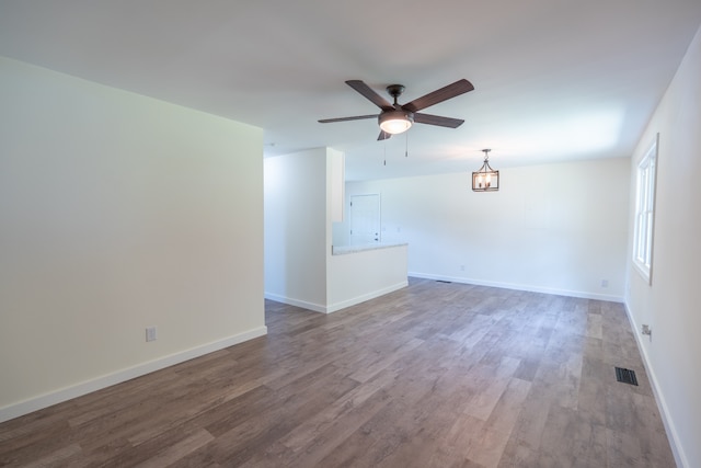 empty room featuring ceiling fan with notable chandelier and hardwood / wood-style flooring