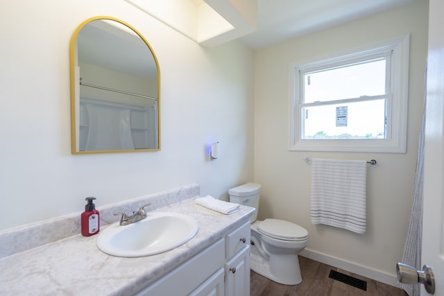 bathroom featuring wood-type flooring, vanity, toilet, and walk in shower