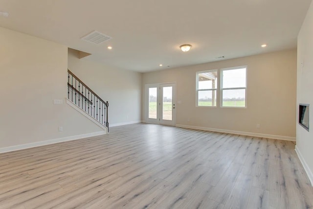 unfurnished living room with french doors and light hardwood / wood-style flooring