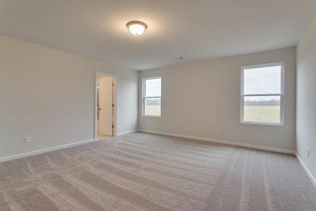 unfurnished room with light colored carpet and plenty of natural light