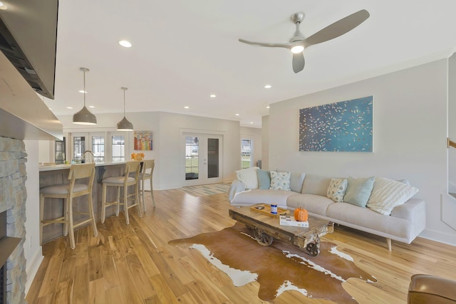 living room with ceiling fan, crown molding, and light hardwood / wood-style flooring