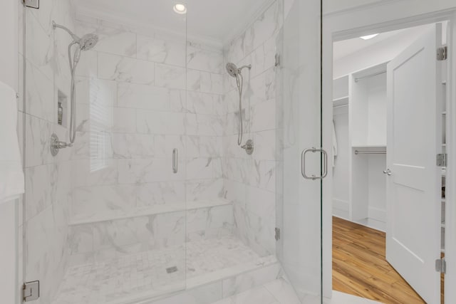 bathroom featuring a shower with door, wood-type flooring, and ornamental molding