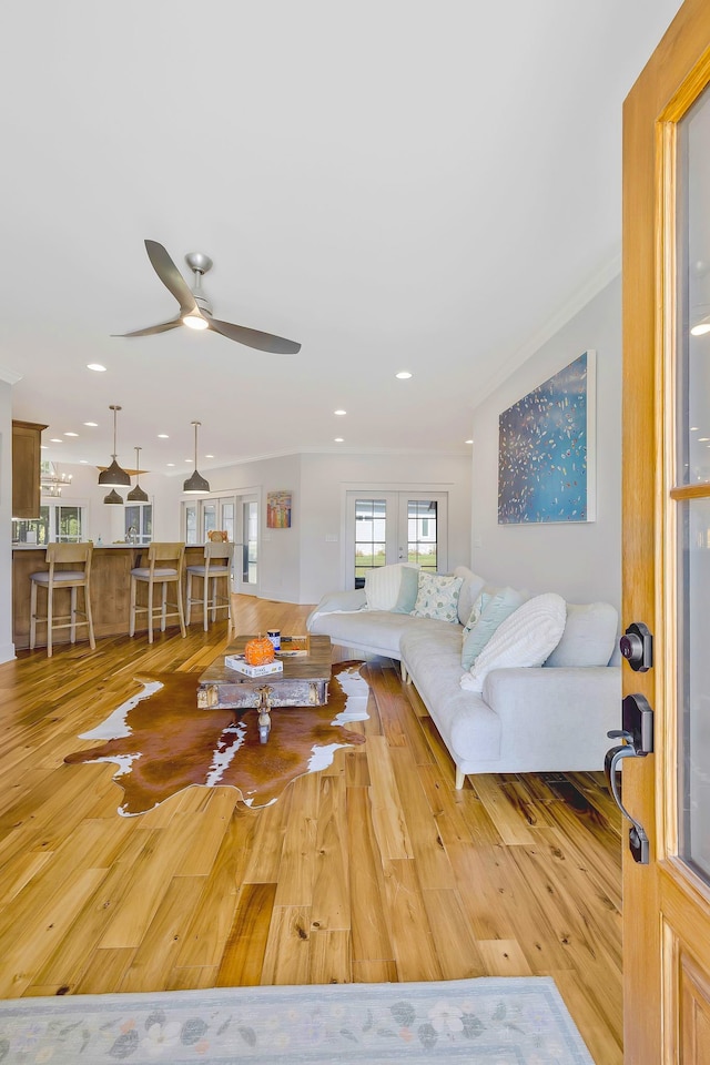 living room featuring light hardwood / wood-style floors, ceiling fan, and ornamental molding