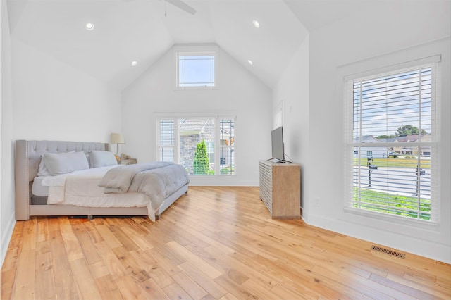 bedroom with multiple windows, ceiling fan, light hardwood / wood-style flooring, and high vaulted ceiling