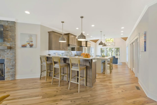 kitchen featuring a breakfast bar area, kitchen peninsula, light hardwood / wood-style flooring, and pendant lighting