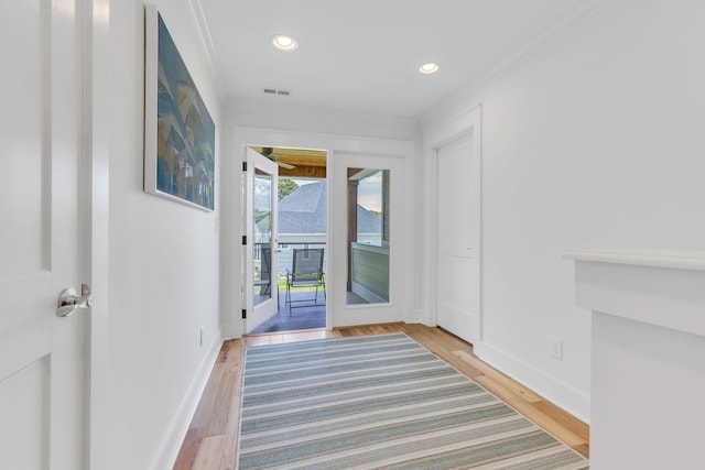 doorway to outside featuring wood-type flooring and crown molding