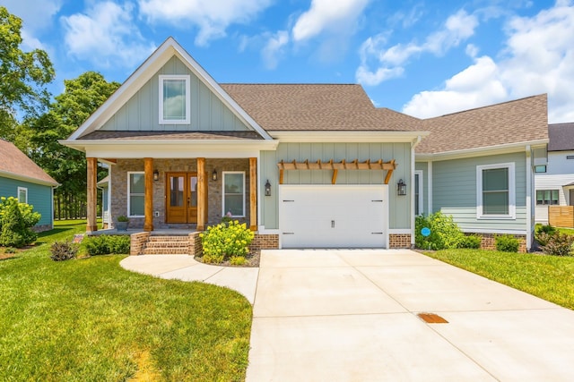 view of front facade with a front yard, french doors, a garage, and covered porch