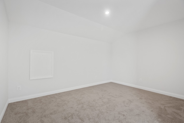 carpeted empty room with lofted ceiling