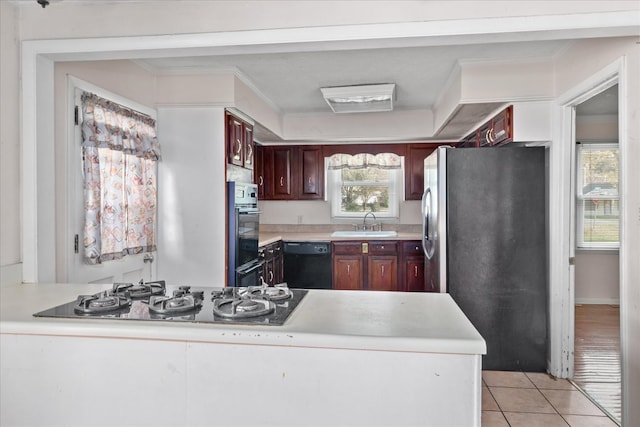 kitchen featuring crown molding, sink, light tile patterned floors, and black appliances