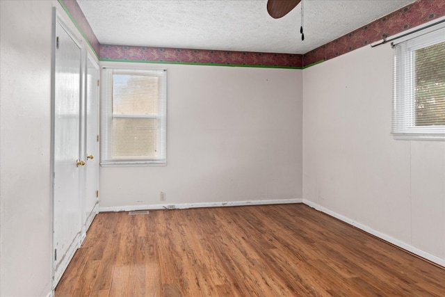 unfurnished room featuring a textured ceiling, hardwood / wood-style flooring, and plenty of natural light