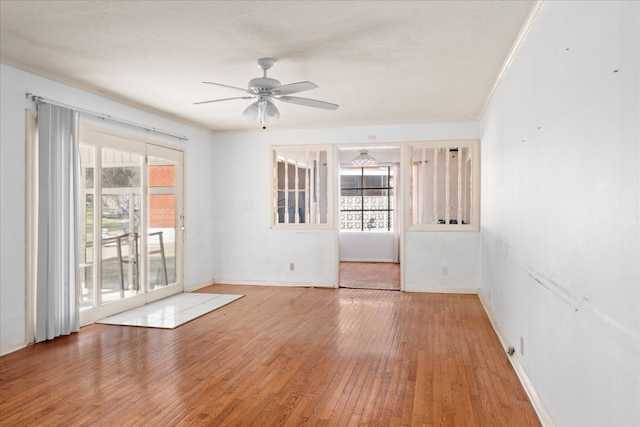 spare room with plenty of natural light, ceiling fan, light wood-type flooring, and crown molding