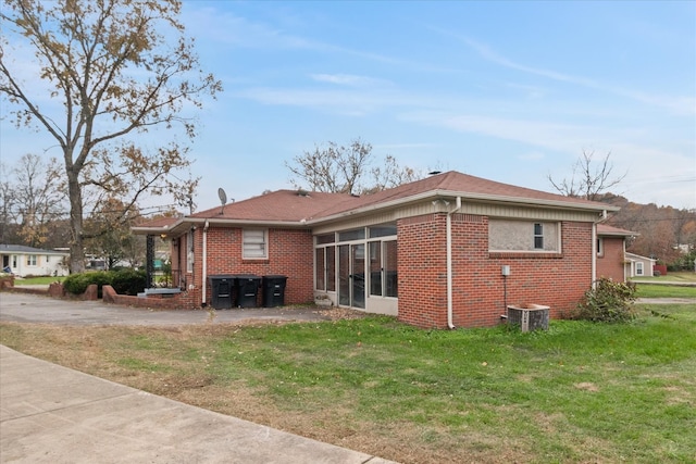 exterior space with a yard, central AC unit, and a sunroom