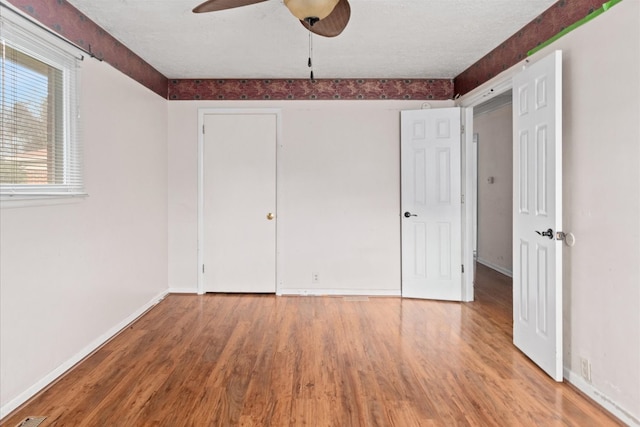 unfurnished bedroom with hardwood / wood-style floors, a textured ceiling, and ceiling fan