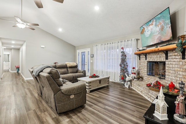 living room with ceiling fan, wood-type flooring, a fireplace, and vaulted ceiling