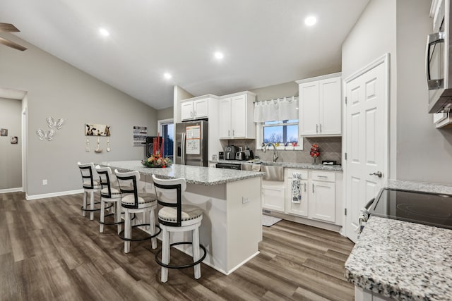 kitchen featuring white cabinets, sink, vaulted ceiling, dark hardwood / wood-style floors, and a kitchen island