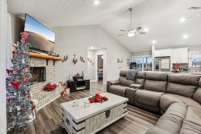 living room featuring ceiling fan, a fireplace, high vaulted ceiling, and hardwood / wood-style flooring