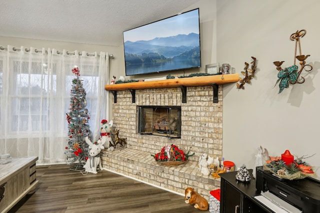 living room featuring a textured ceiling, dark hardwood / wood-style flooring, and a brick fireplace