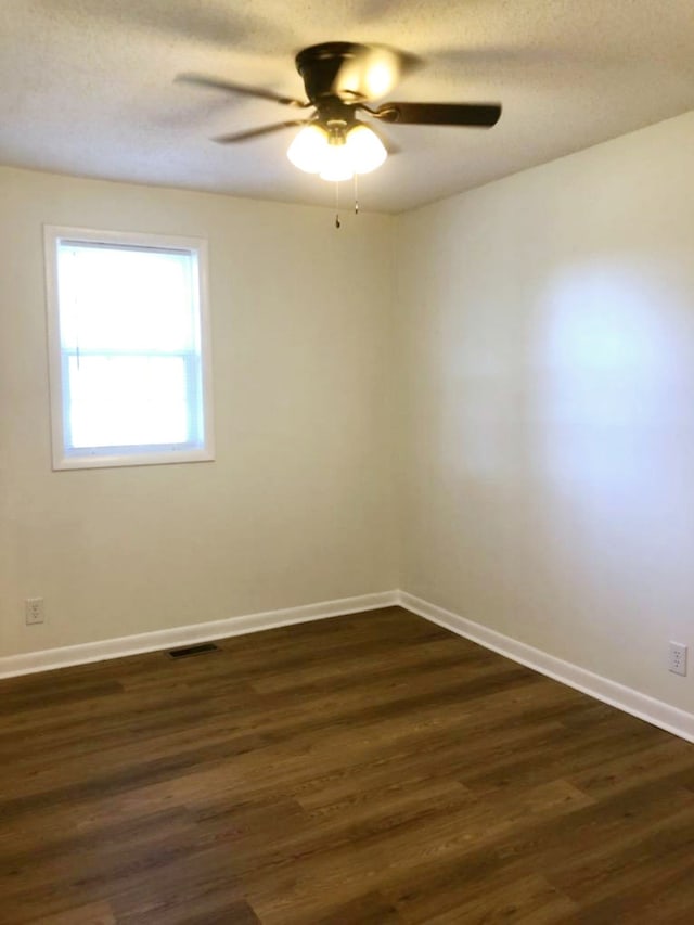 unfurnished room with ceiling fan, dark wood-type flooring, and a textured ceiling