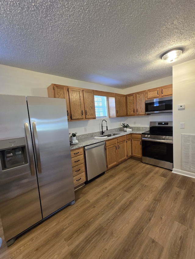 kitchen featuring a textured ceiling, sink, dark hardwood / wood-style floors, and appliances with stainless steel finishes