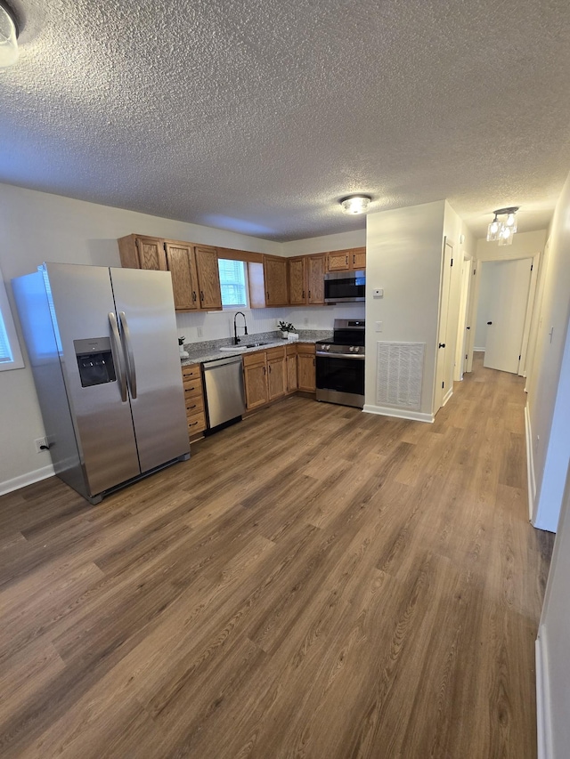 kitchen with sink, hardwood / wood-style floors, a textured ceiling, and appliances with stainless steel finishes