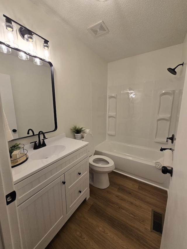 full bathroom with bathtub / shower combination, wood-type flooring, a textured ceiling, and toilet