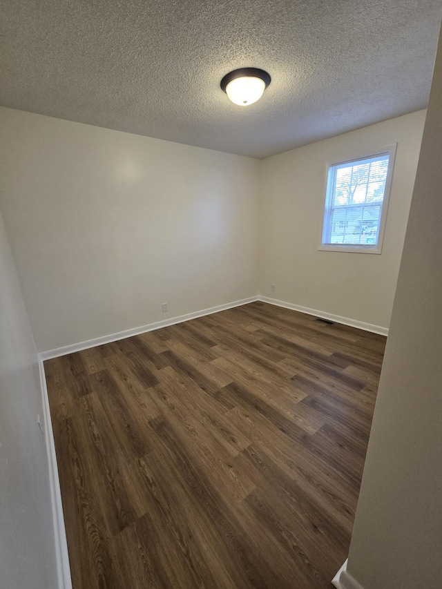 unfurnished room featuring a textured ceiling and dark wood-type flooring