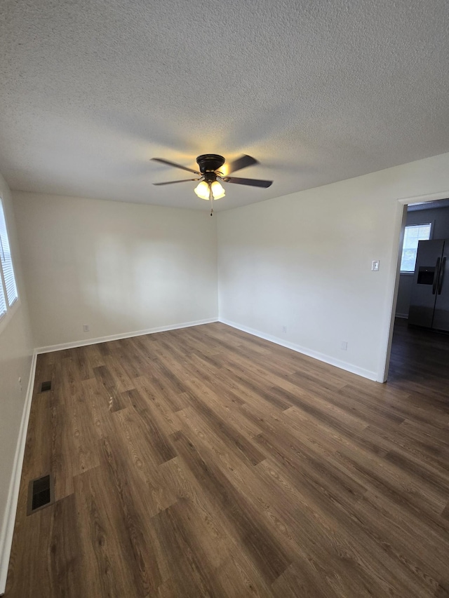 unfurnished room featuring dark hardwood / wood-style floors, ceiling fan, and a textured ceiling