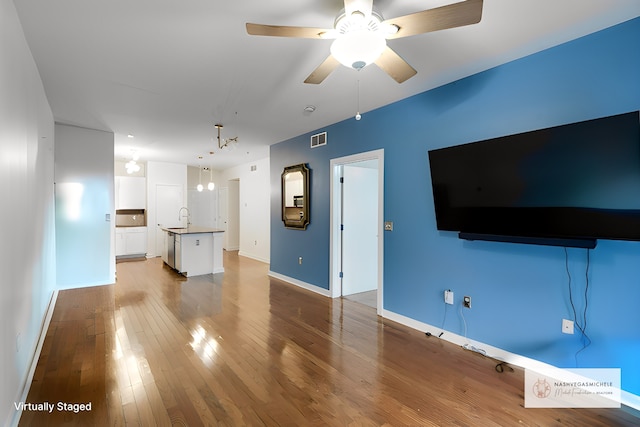 unfurnished living room with ceiling fan with notable chandelier, hardwood / wood-style flooring, and sink